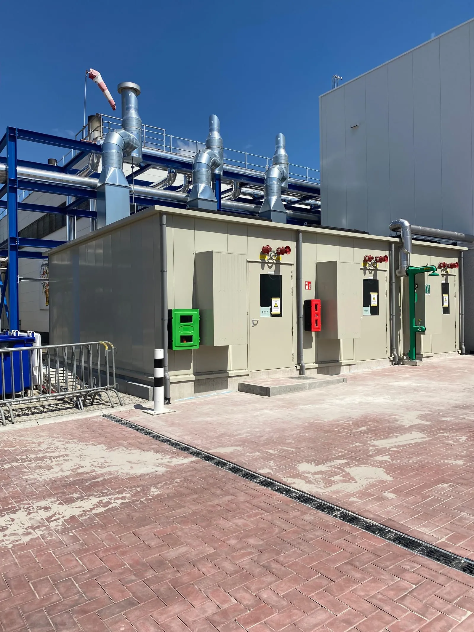 Geluidsomkasting met ventilatiekanalen naast een industrieel gebouw