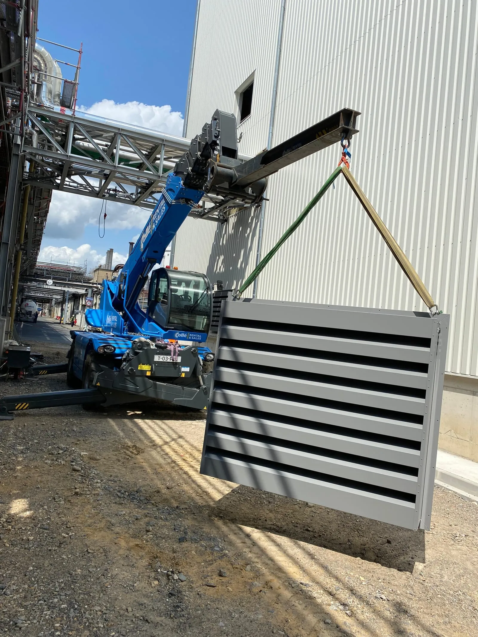 Geluidswerend rooster hangend aan de torenkraan tijdens de montage